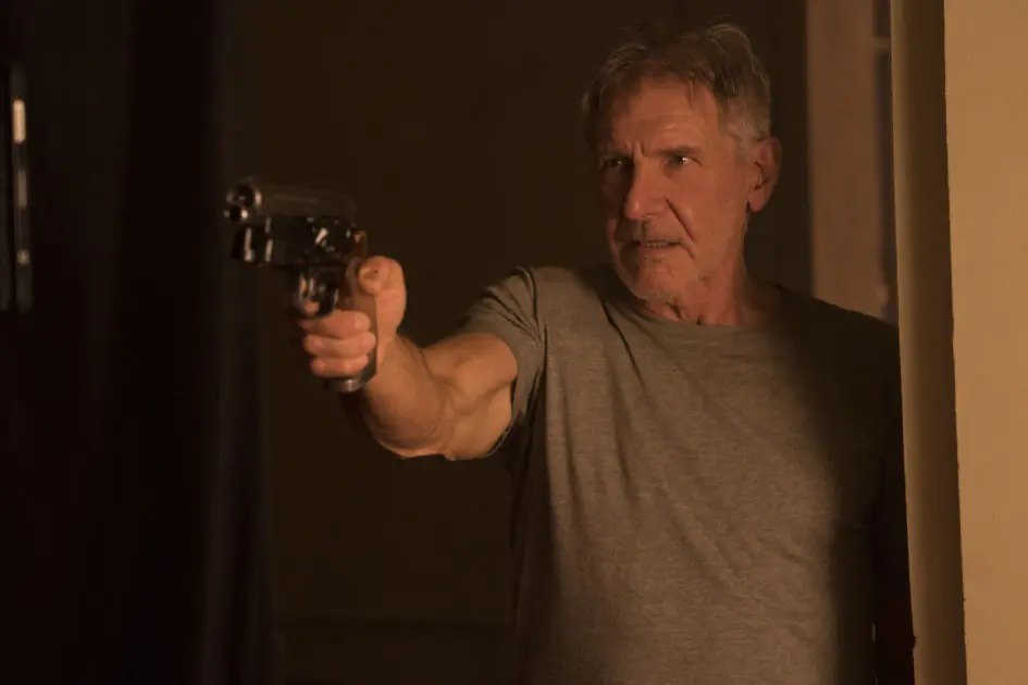 A man aims a gun in a dark room.