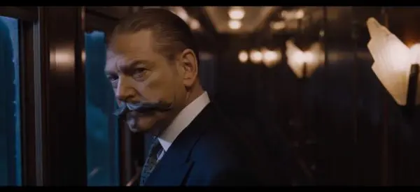 Man with mustache looking out train window.