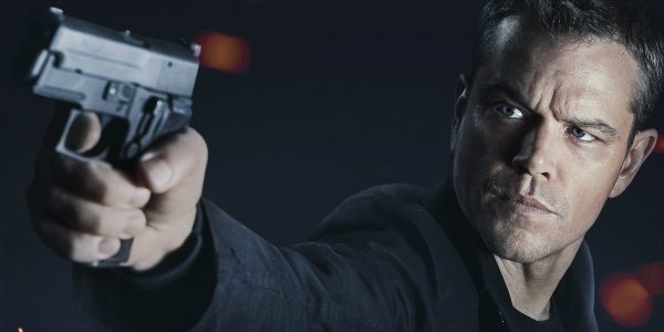 Man holding a gun, dark background.