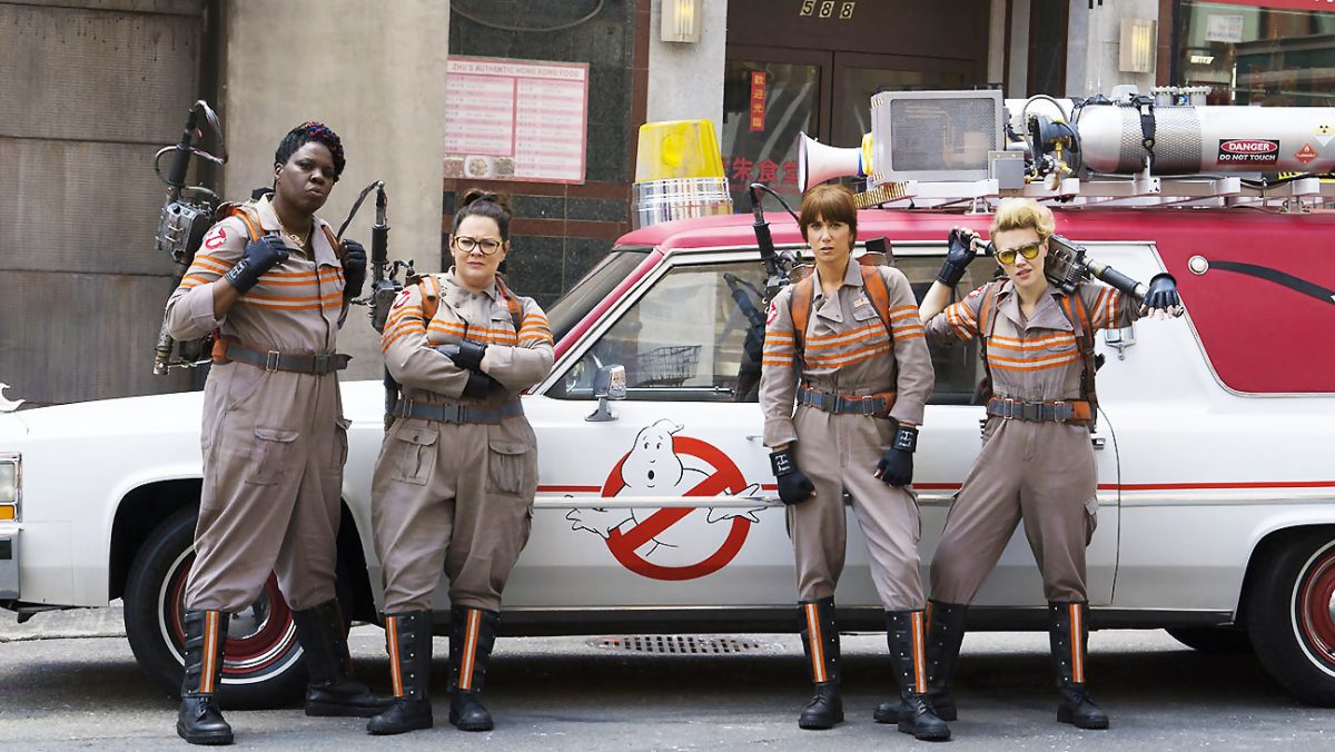 Four Ghostbusters standing in front of Ecto-1.