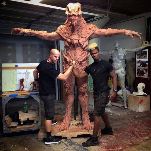 Clay monster sculpture with two men.