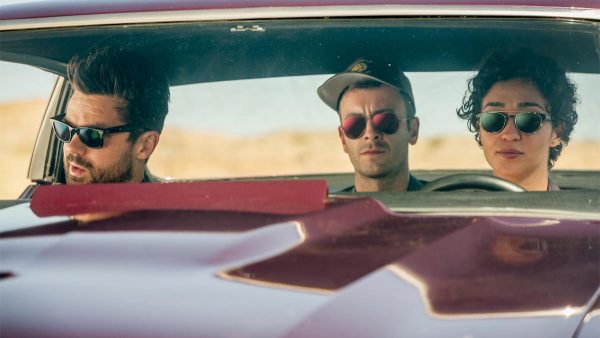 Three people wearing sunglasses in a car.