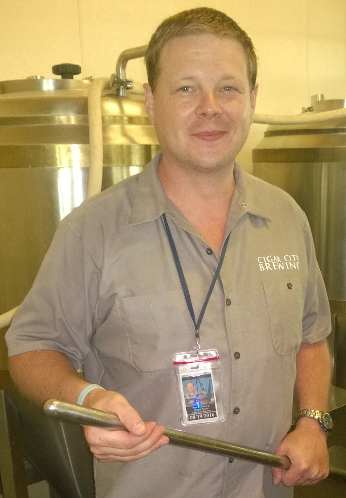 Man holding metal rod at Cigar City Brewing.