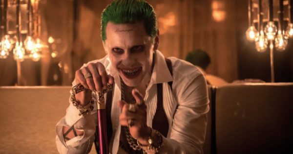 The Joker smiles holding a cane.