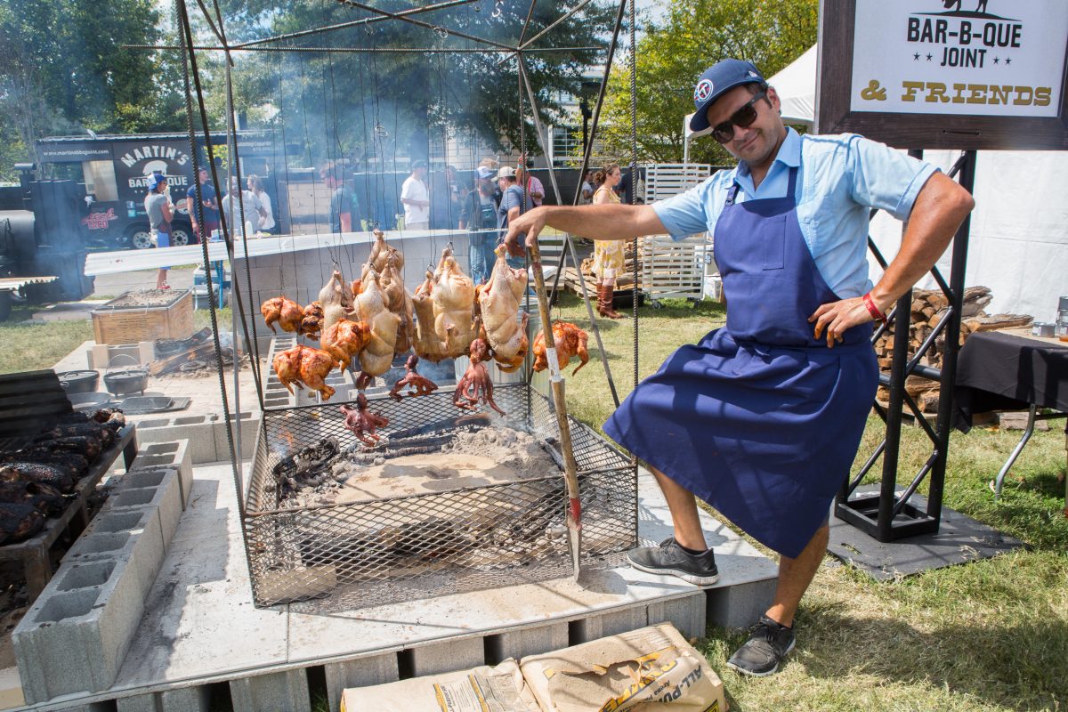 Man grilling chicken and octopus at a barbecue joint.