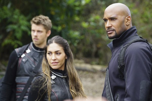 Three people in a forest, looking serious.