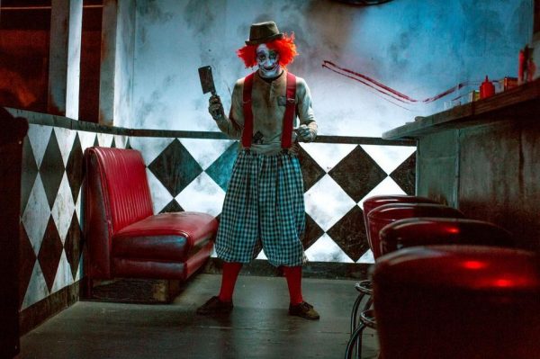 Creepy clown holding a cleaver in diner.