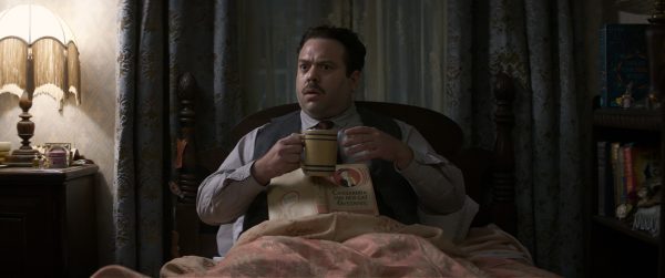 Man in bed holding a mug and book.