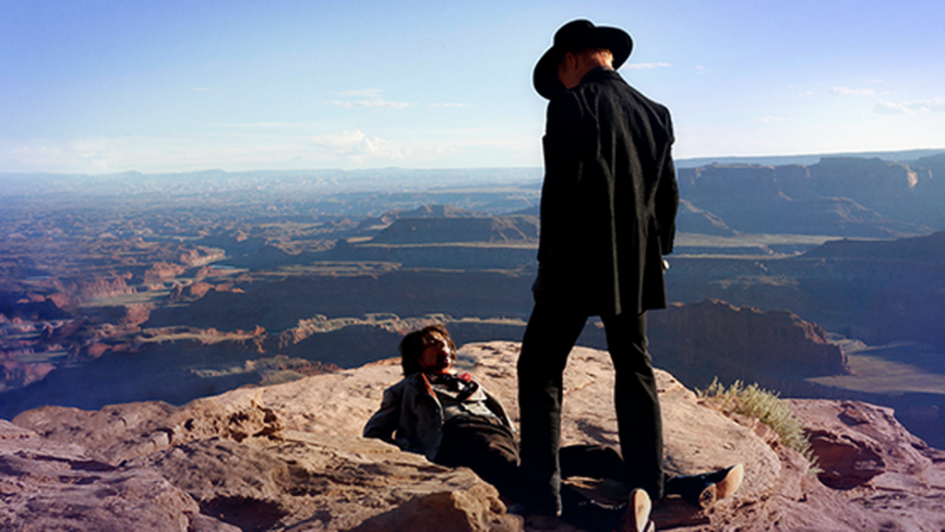 Two men on a cliff overlooking a canyon.