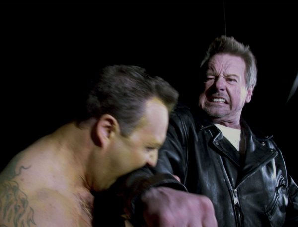 Man in leather jacket attacks shirtless man.