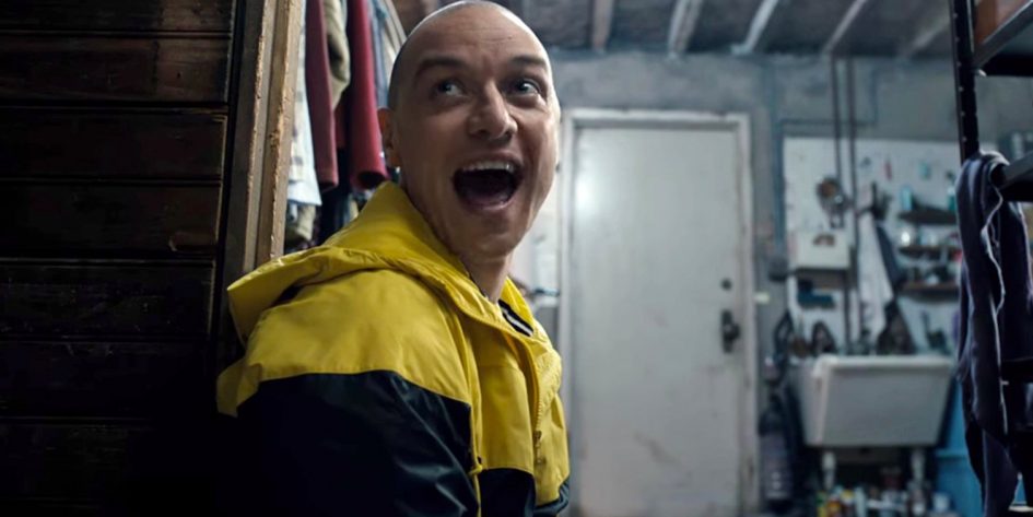 Man in yellow jacket laughs in a garage.