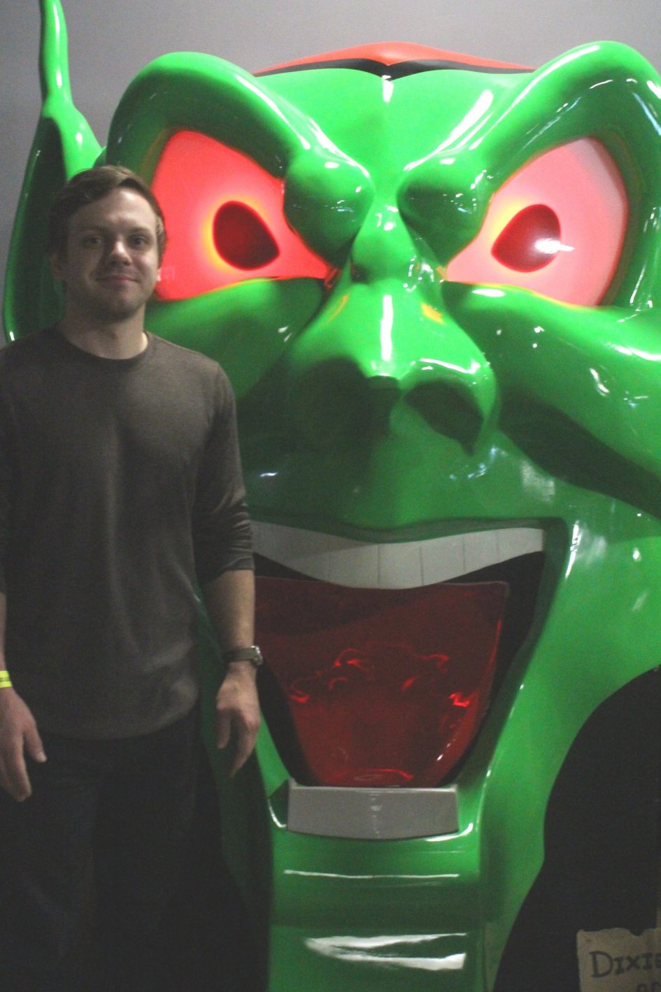 Man standing near green monster face.