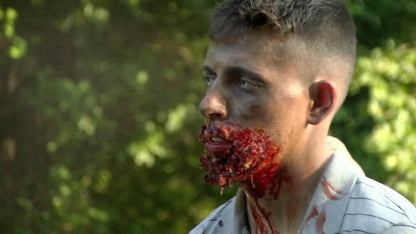 Man with a bloody face in a forest.