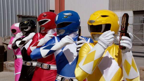 Power Rangers stand together in suits.