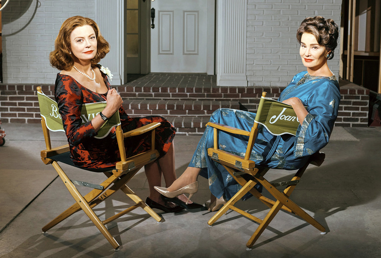 Two women sitting on director's chairs.