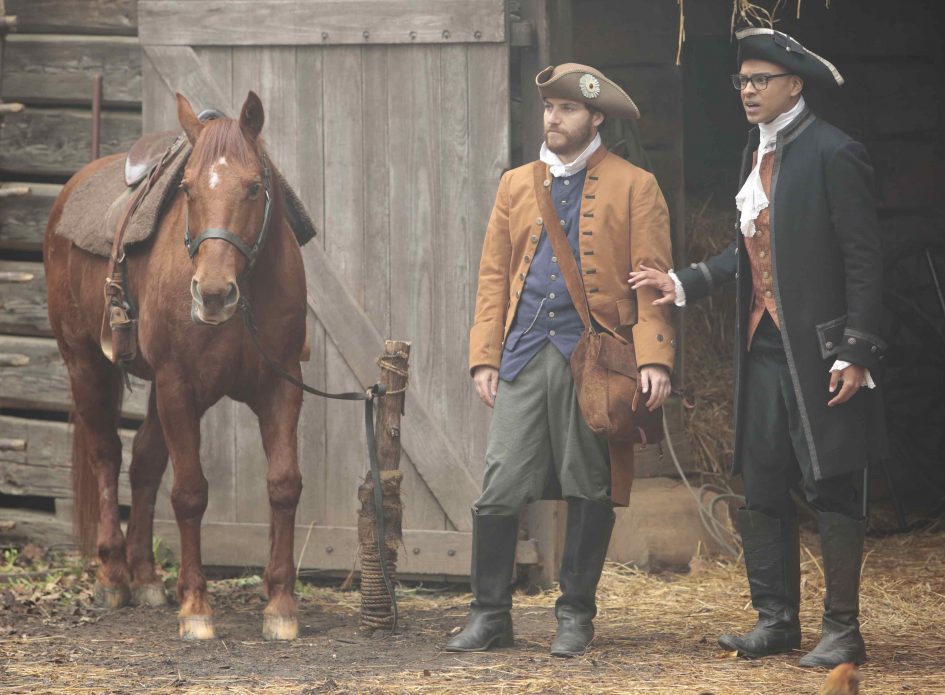 Two men in colonial garb with a horse.