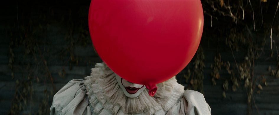 Pennywise the clown holding a red balloon.