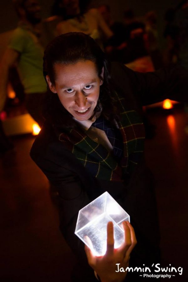 Man holding glowing cube in dark room.