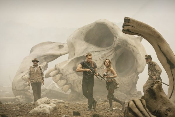 Four people stand near a giant skull.