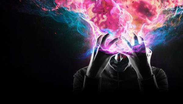 Man with hands over his head, surrounded by colorful energy.