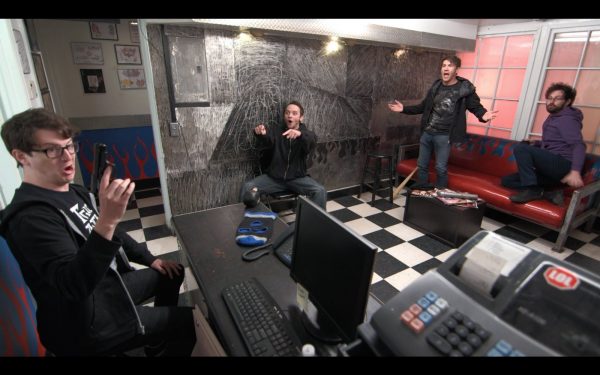 Four men in a room with a cash register.