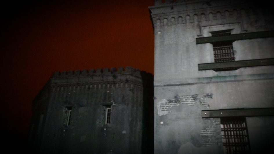 Two stone buildings with barred windows.