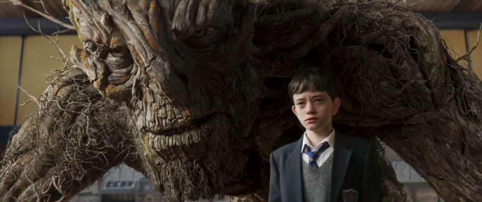 A young boy stands before a large, menacing tree creature.