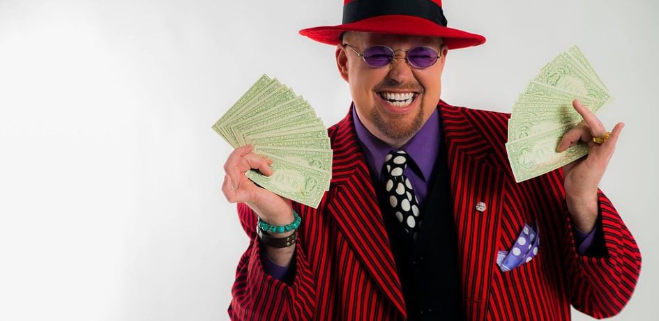 Man in red suit holding money, smiling.