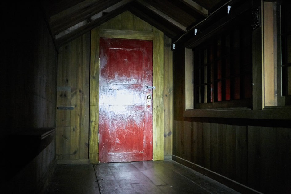 Red door in dark wooden hallway.