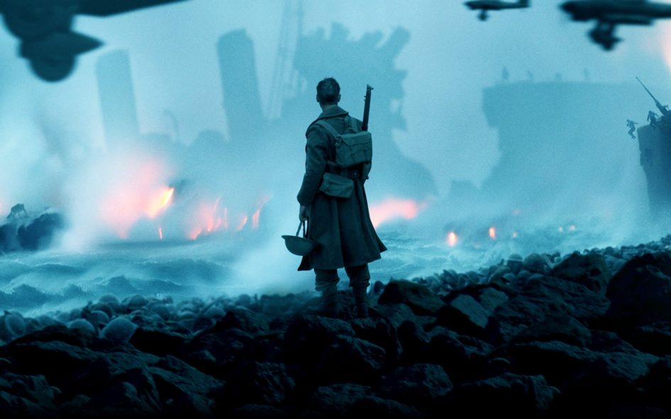 A lone soldier stands on a rocky shore.