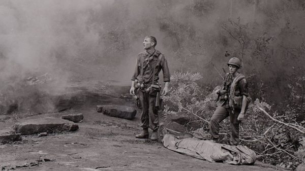 Two soldiers in jungle setting, one looking up.