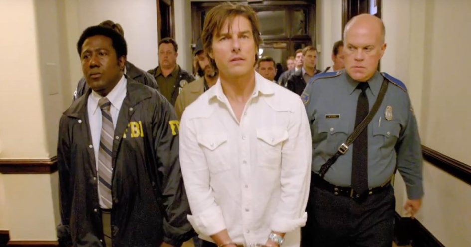 Tom Cruise in handcuffs, escorted by police.