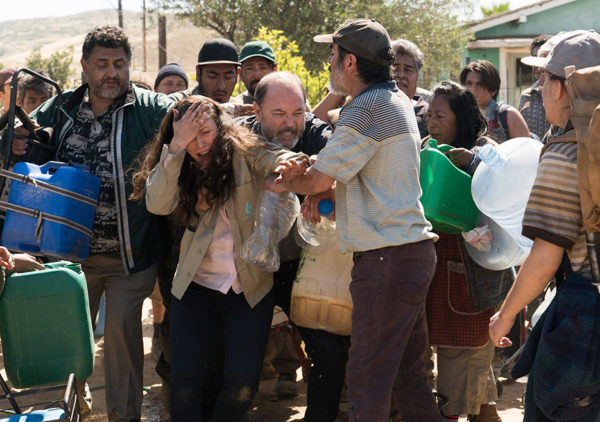 A woman cries while carrying water jugs.