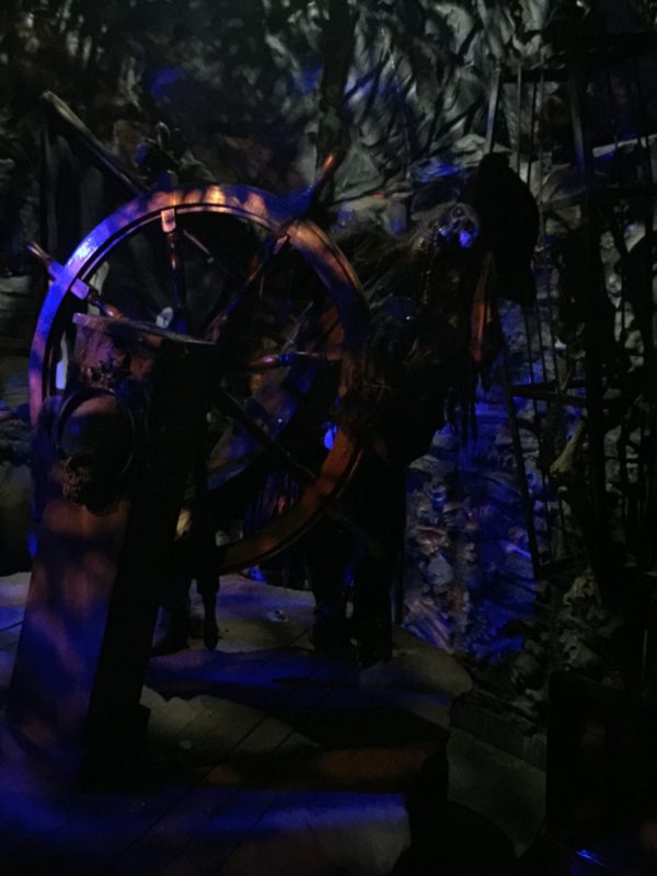 A wooden ship wheel in a dark room.