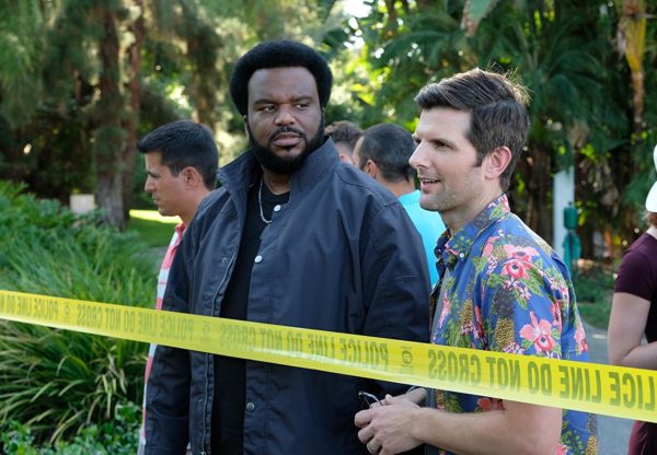 Two men stand near crime scene tape.