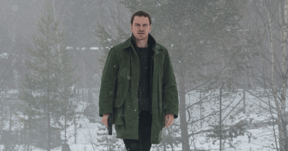 Man in green coat walks in snow.