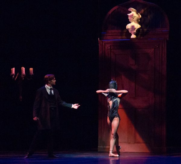 A man and a woman dance in a dark room.