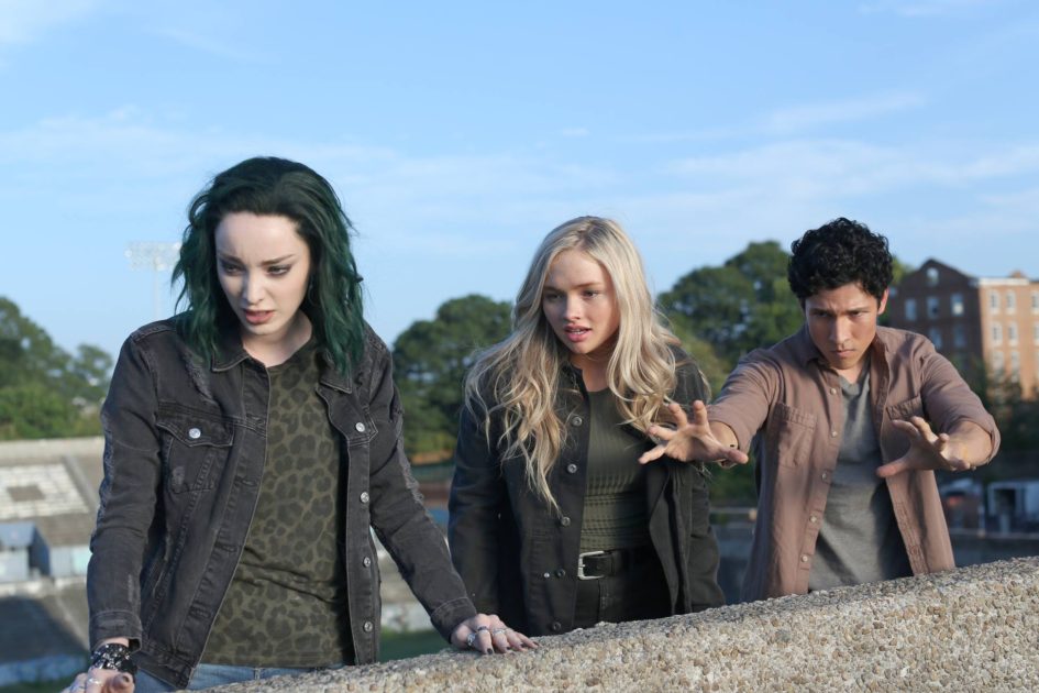 Three young adults looking surprised outdoors.