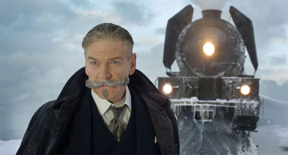 A man with a mustache stands near a train.