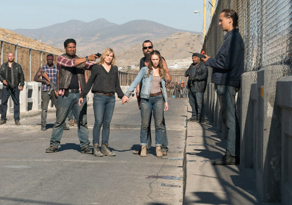 Group of people standing by a fence.