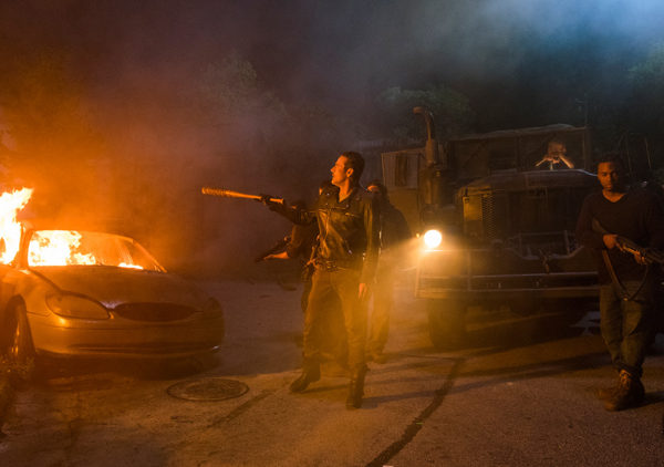 Man holding a bat near a burning car.