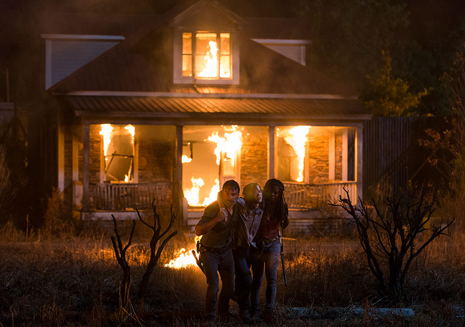 Three people flee burning house at night.