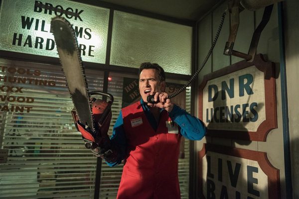 Man in red vest holding a chainsaw.