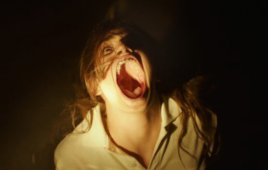 A woman screams with her mouth open wide.