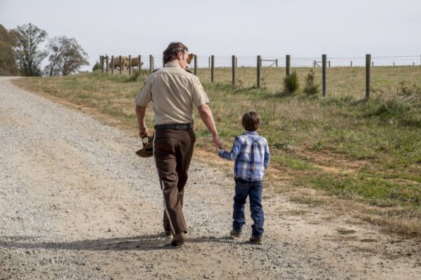 Man and boy walking down a dirt road.