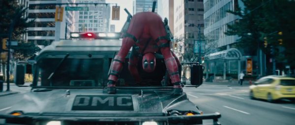 Deadpool hanging from a moving vehicle.