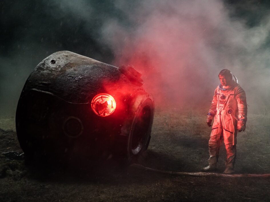 Russian cosmonaut standing beside smoking space capsule