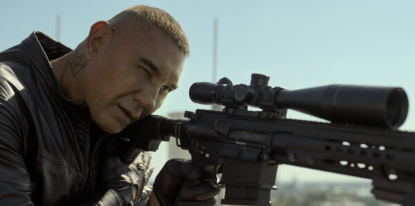 Man aiming a rifle with a scope.